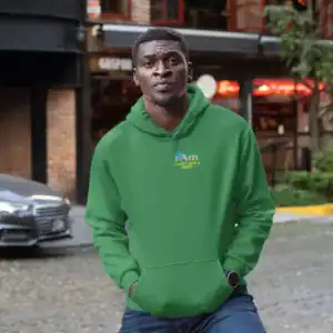 Young man in green hoodie standing outdoors in urban setting.